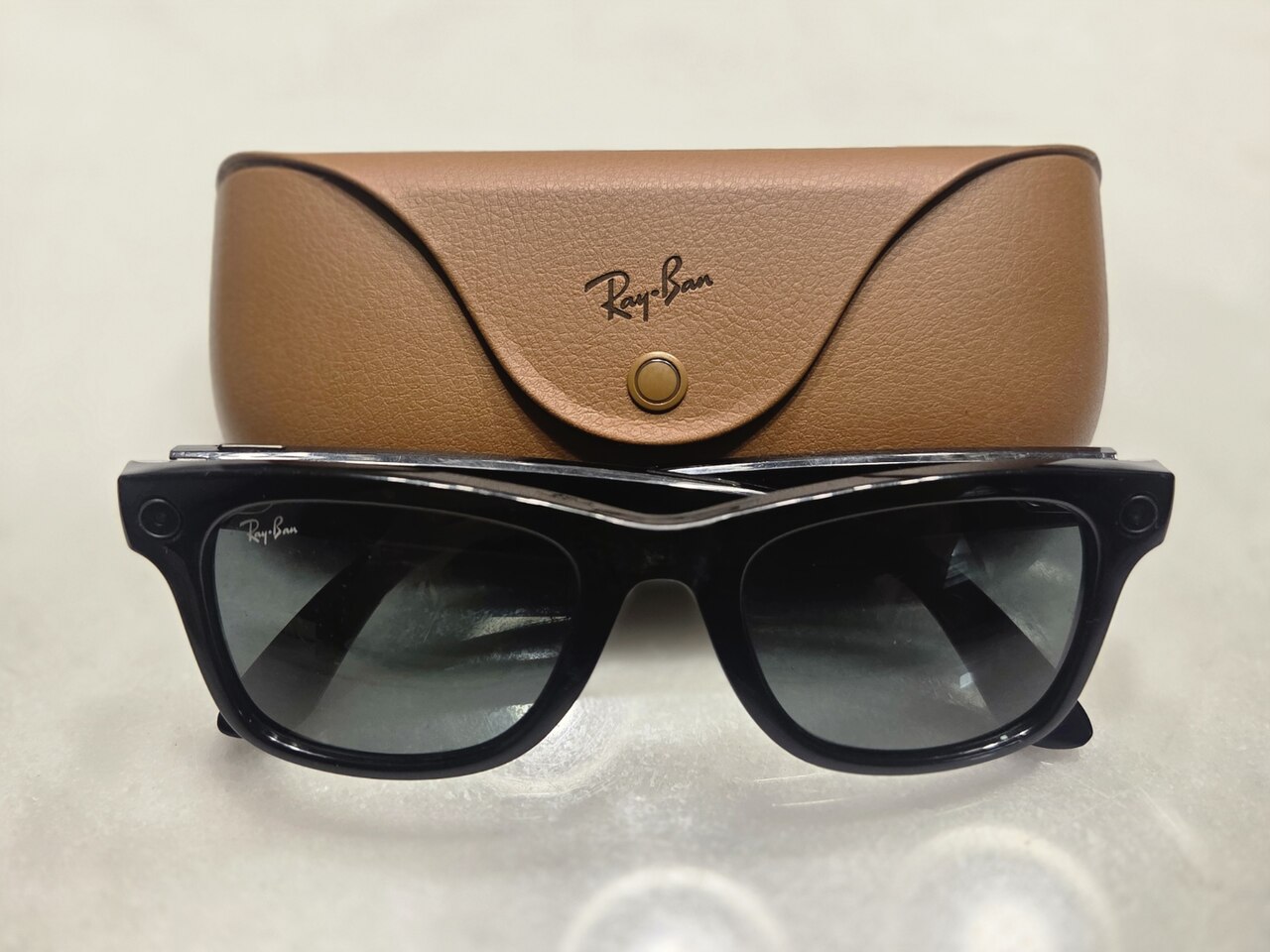 Des lunettes connectées Ray-Ban Meta noires posées à côté de leur boîtier de charge