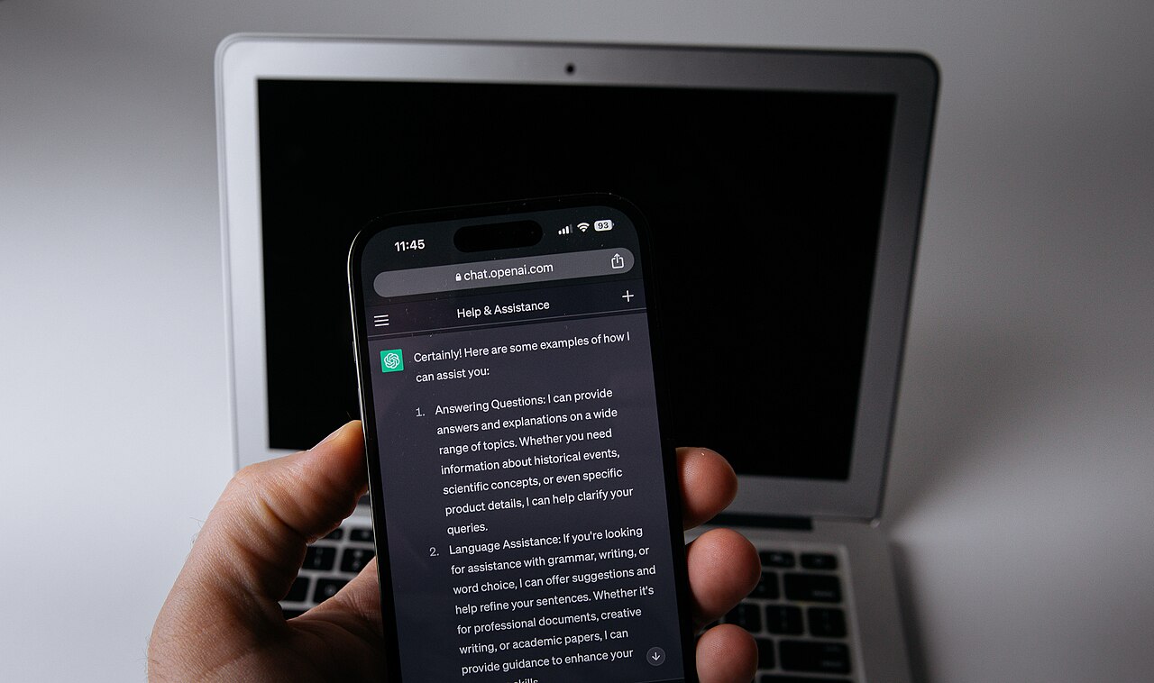 Un téléphone portable avec l'application ChatGPT ouverte à côté d'un ordinateur portable