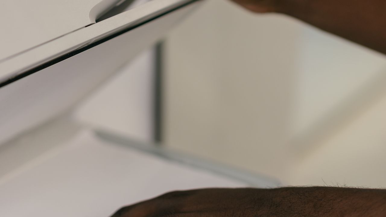 Hands adjusting a document on a scanner tray in an office