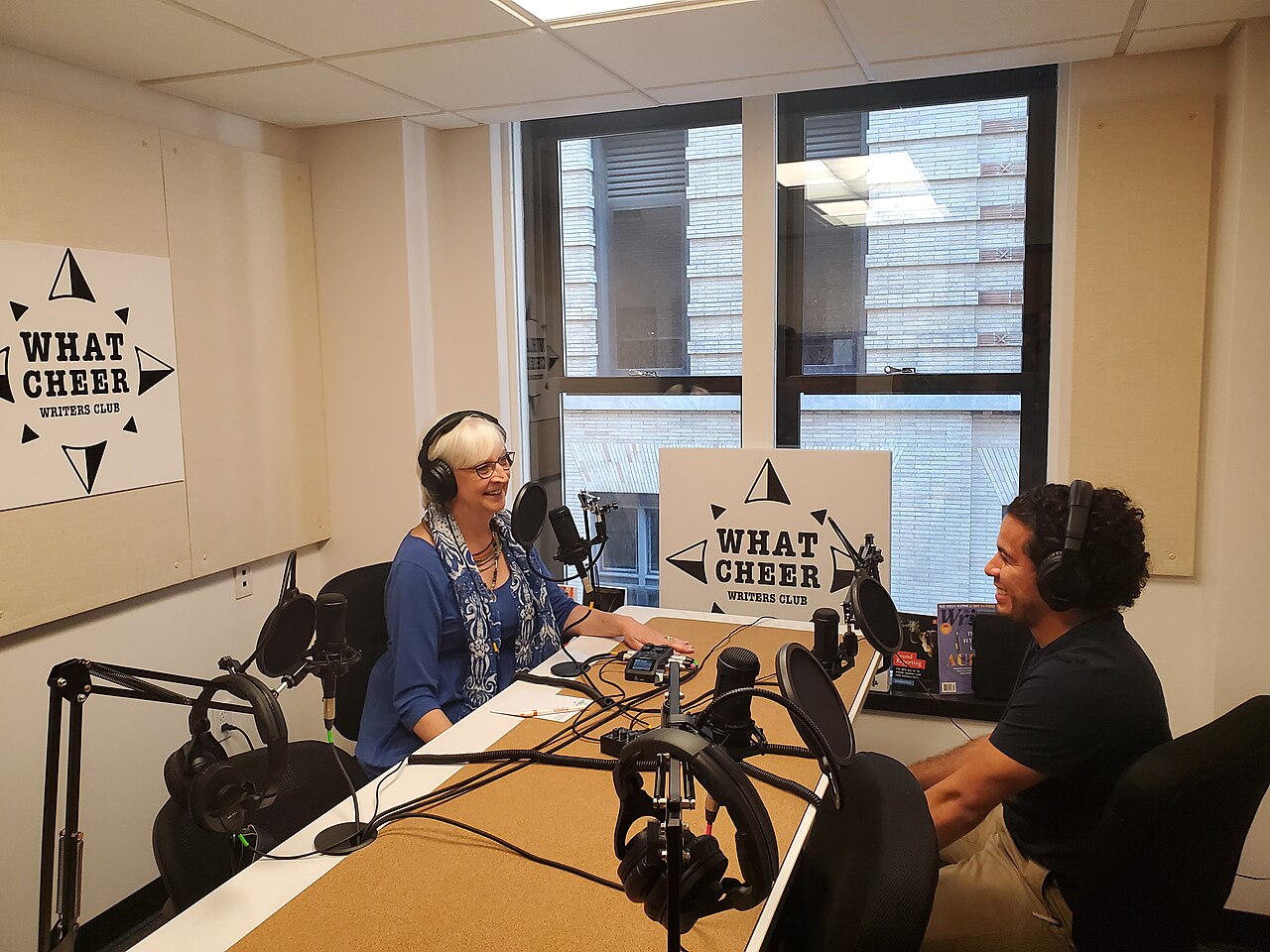 A podcast studio with several microphones and people talking