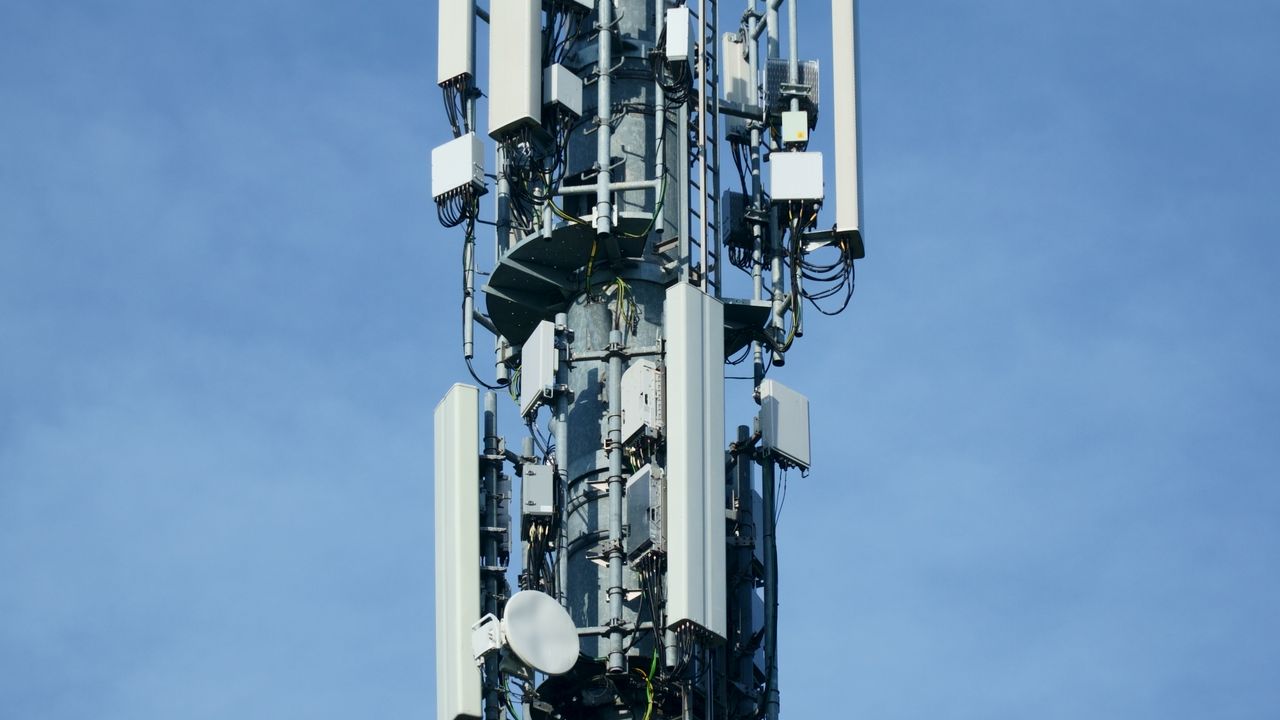 A telecommunications transmission mast with multiple antennas against a blue sky