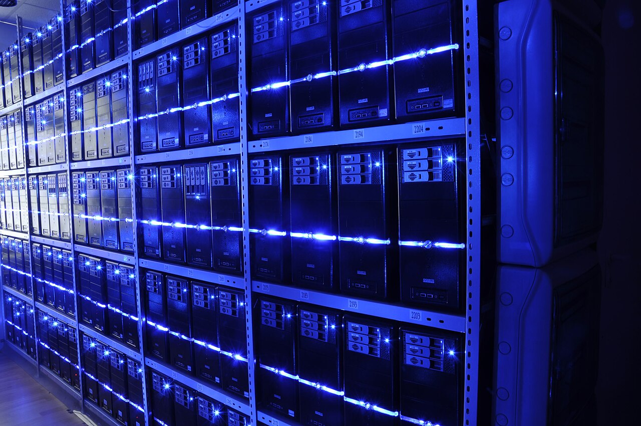 Server racks in a data center, rows of network cabling and blinking status lights