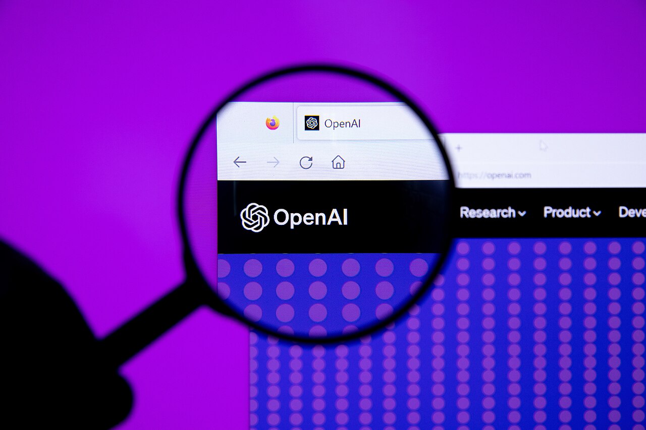 The OpenAI logo displayed on a screen, magnified with a magnifying glass